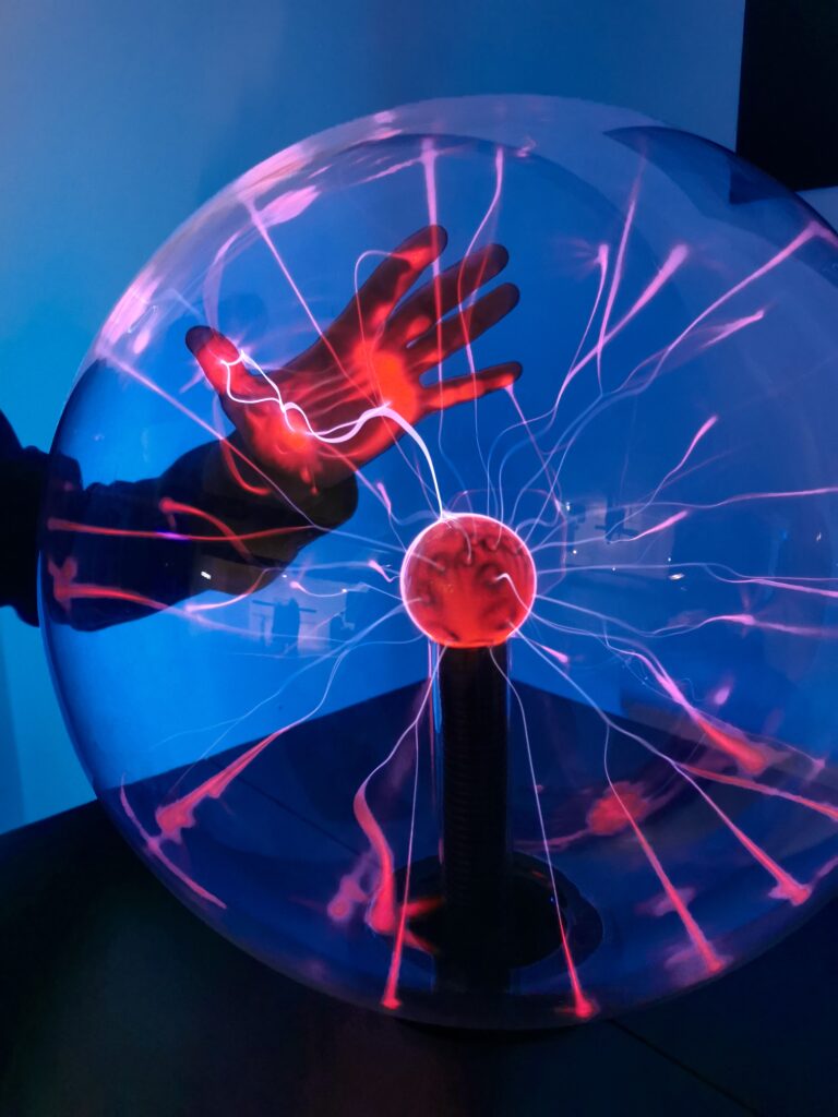 A mesmerizing scene of a hand interacting with an illuminated plasma globe emitting vivid light patterns.