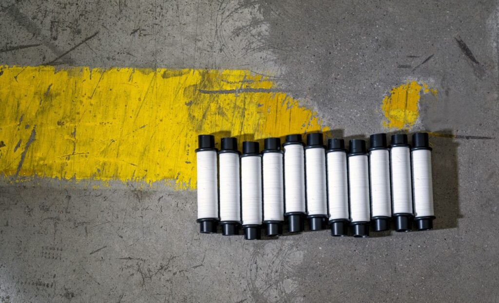Plastic rolls aligned by a yellow road marking on concrete.