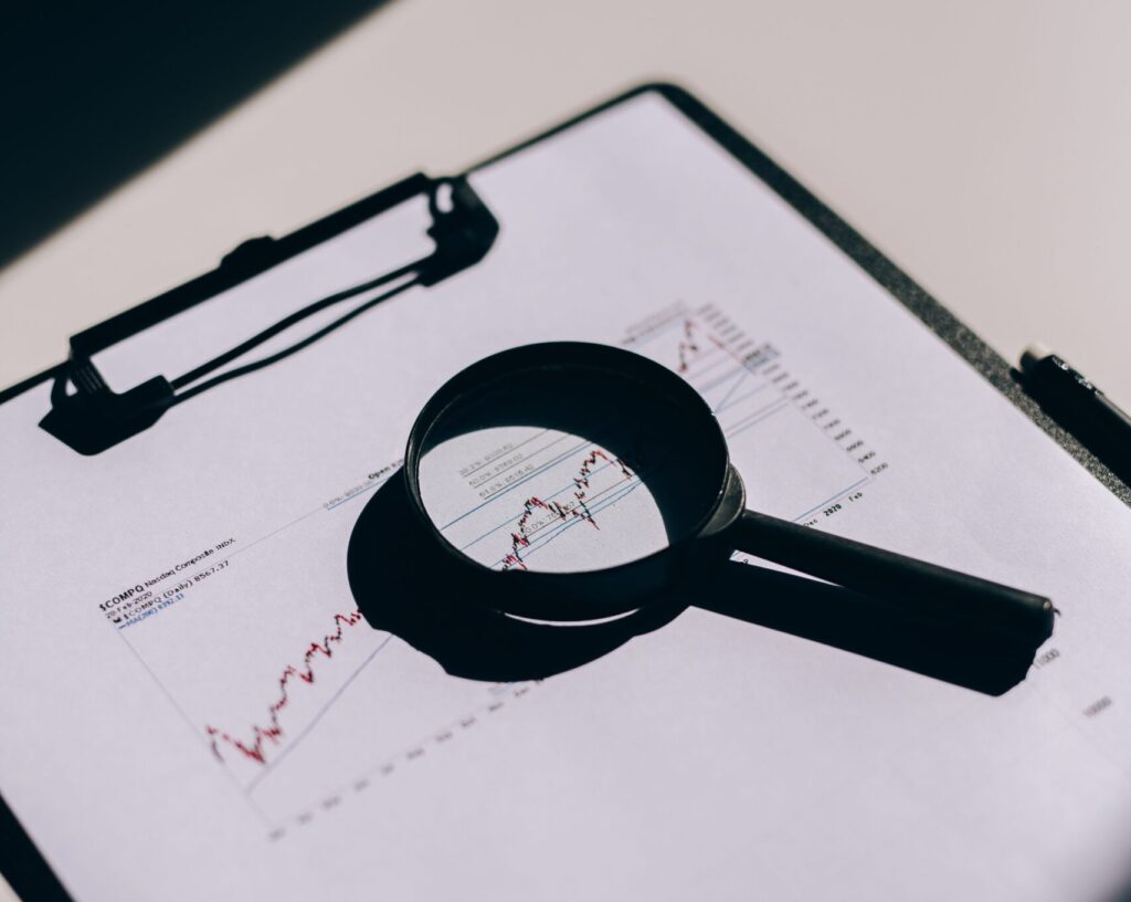 Detailed close-up of financial documents with graphs and magnifying glass on a clipboard.