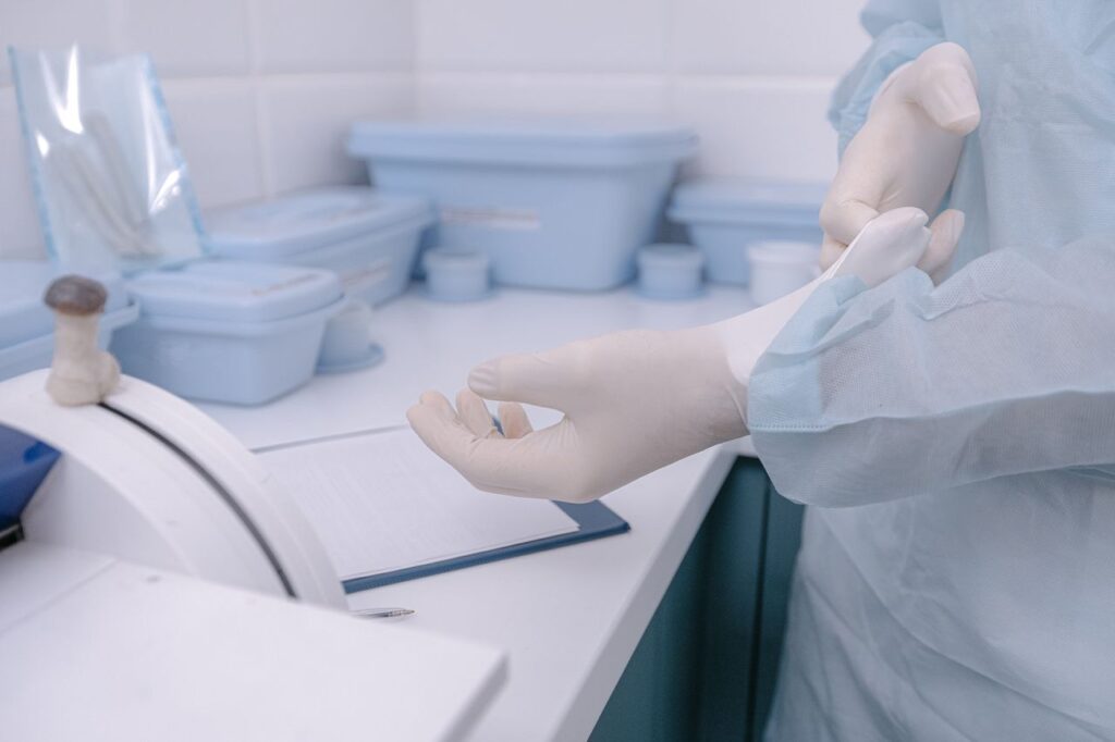 A health worker dons gloves in a clean, sterile medical setting, emphasizing safety and hygiene.